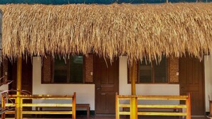 Un edificio con tetto di paglia e panche di legno davanti.