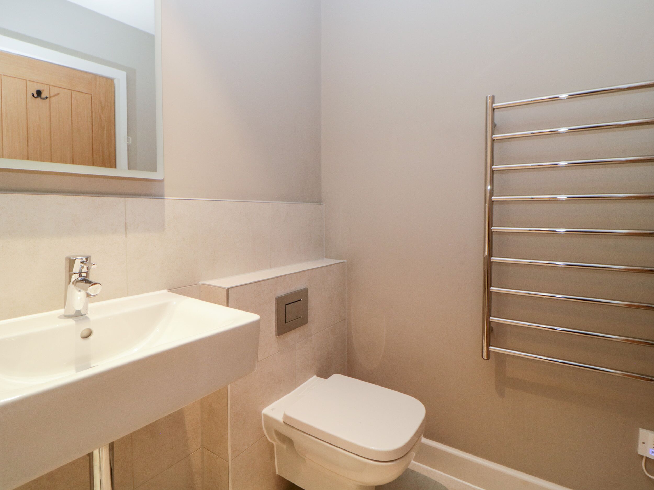 Un baño con lavamanos blanco, inodoro y toallero.