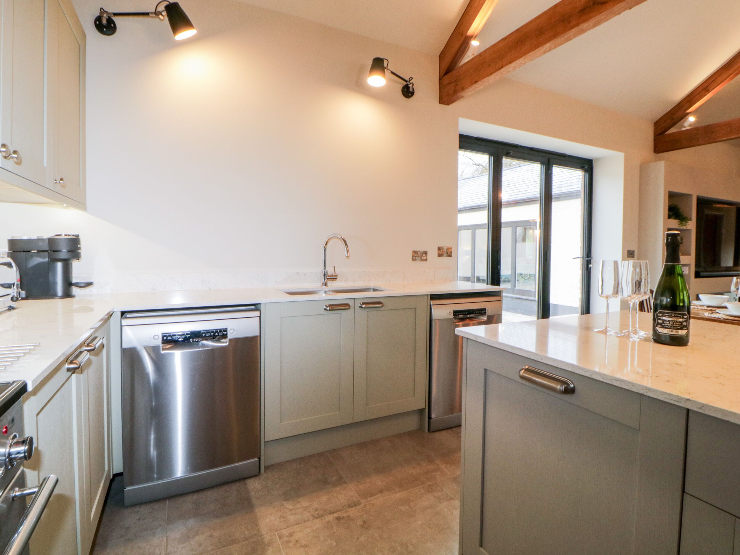 Een moderne keuken met roestvrijstalen apparatuur, een groot raam en een fles champagne op het aanrecht.