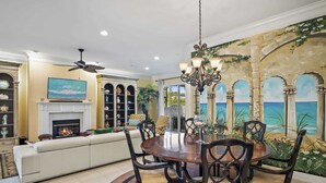 A dining area with a round table, chairs, and a chandelier. - Golf Cart & 4 Bikes! 3 Min Walk to Pool & Hot Tub! 8 Min to Beach! New Listing! ~ Sunshine Retreat at Destiny West (Destin)