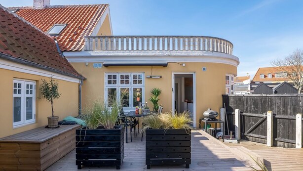 A residential property with a curved balcony, a wooden deck, and a small patio area with outdoor furniture and plants. - "Yorick" - 300m from the sea by Interhome (Skagen)