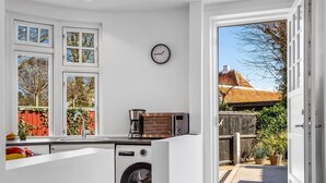 A compact kitchen with a washing machine, a coffee maker, and a clock on the wall. - "Yorick" - 300m from the sea by Interhome (Skagen)