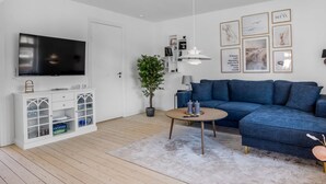 A modern living room with a flat-screen TV, a blue sofa, a round coffee table, and a potted plant. - "Yorick" - 300m from the sea by Interhome (Skagen)