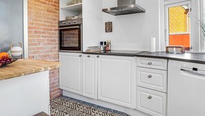 A kitchen with white cabinets, a stainless steel range hood, and a brick wall. - "Yorick" - 300m from the sea by Interhome (Skagen)