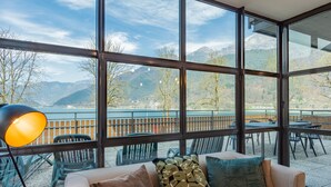 A modern room with large windows offering a mountain view. - Superior by Interhome (Lago di Ledro)