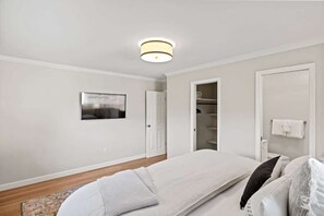 A bedroom with a bed, a bedside table, a nightstand, a wardrobe, and a ceiling light fixture.
