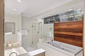 A modern bathroom with a large bathtub, a glass shower enclosure, and a wooden vanity.