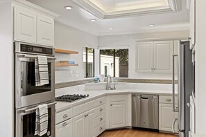 A modern kitchen with white cabinetry, stainless steel appliances, and a dishwasher.