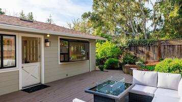 A house with a deck, a glass-top table, and a white sofa.