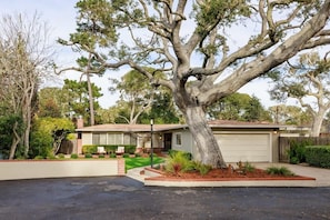 A single-story house with a large tree in the front yard.