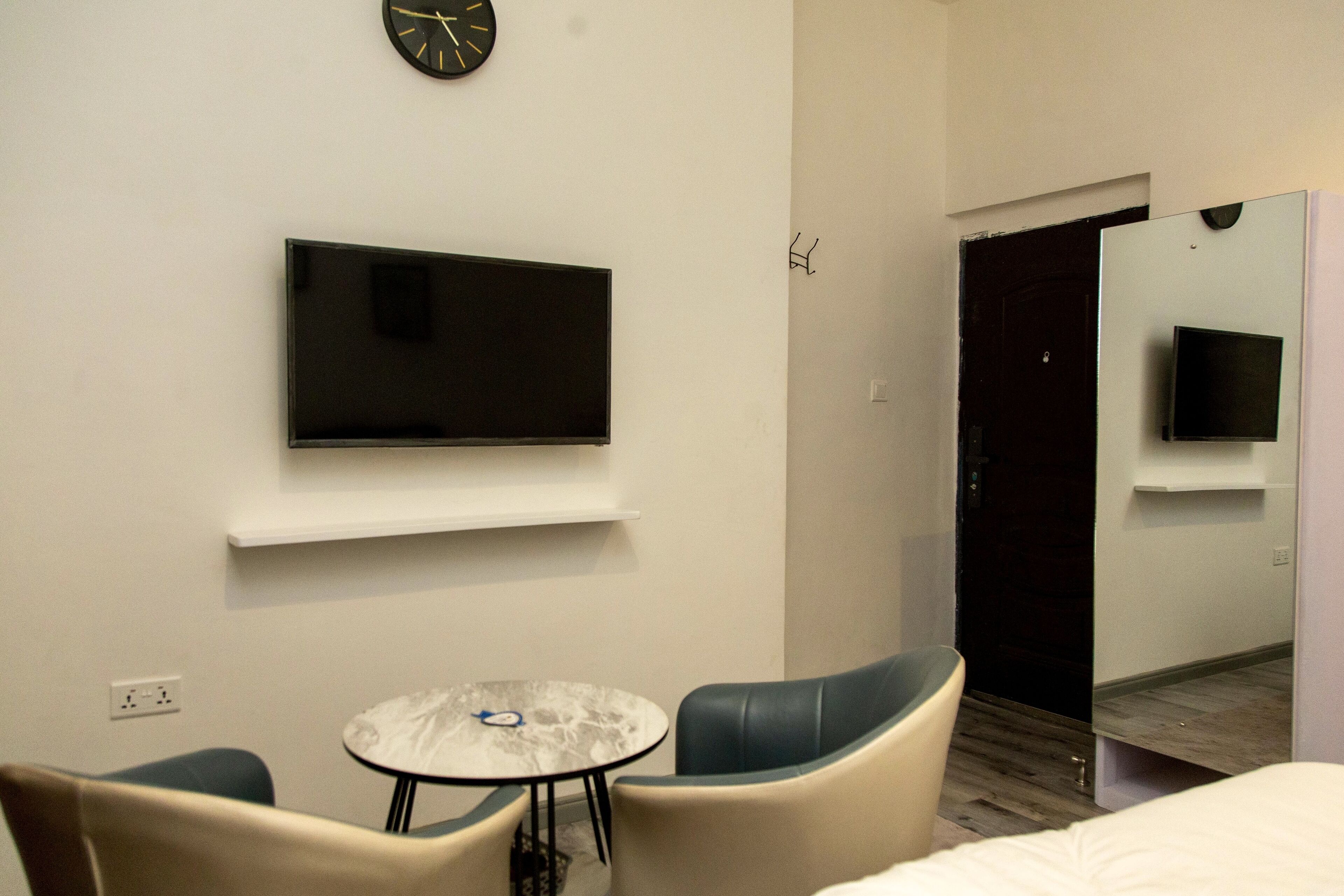 Une chambre d’hôtel équipée d’un téléviseur à écran plat fixé au mur, d’une petite table ronde, de deux chaises et d’un lit.
