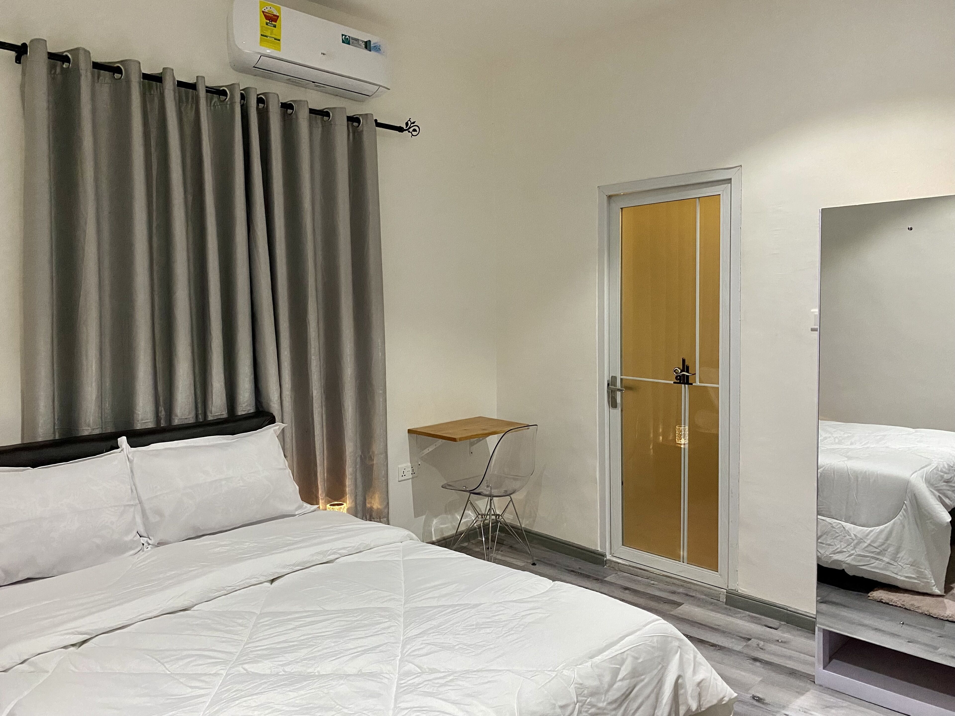 Una habitación de hotel con una cama, una mesita, una silla, un armario y una puerta.