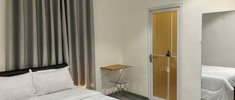 Una habitación de hotel con una cama, una mesita, una silla, un armario y una puerta.