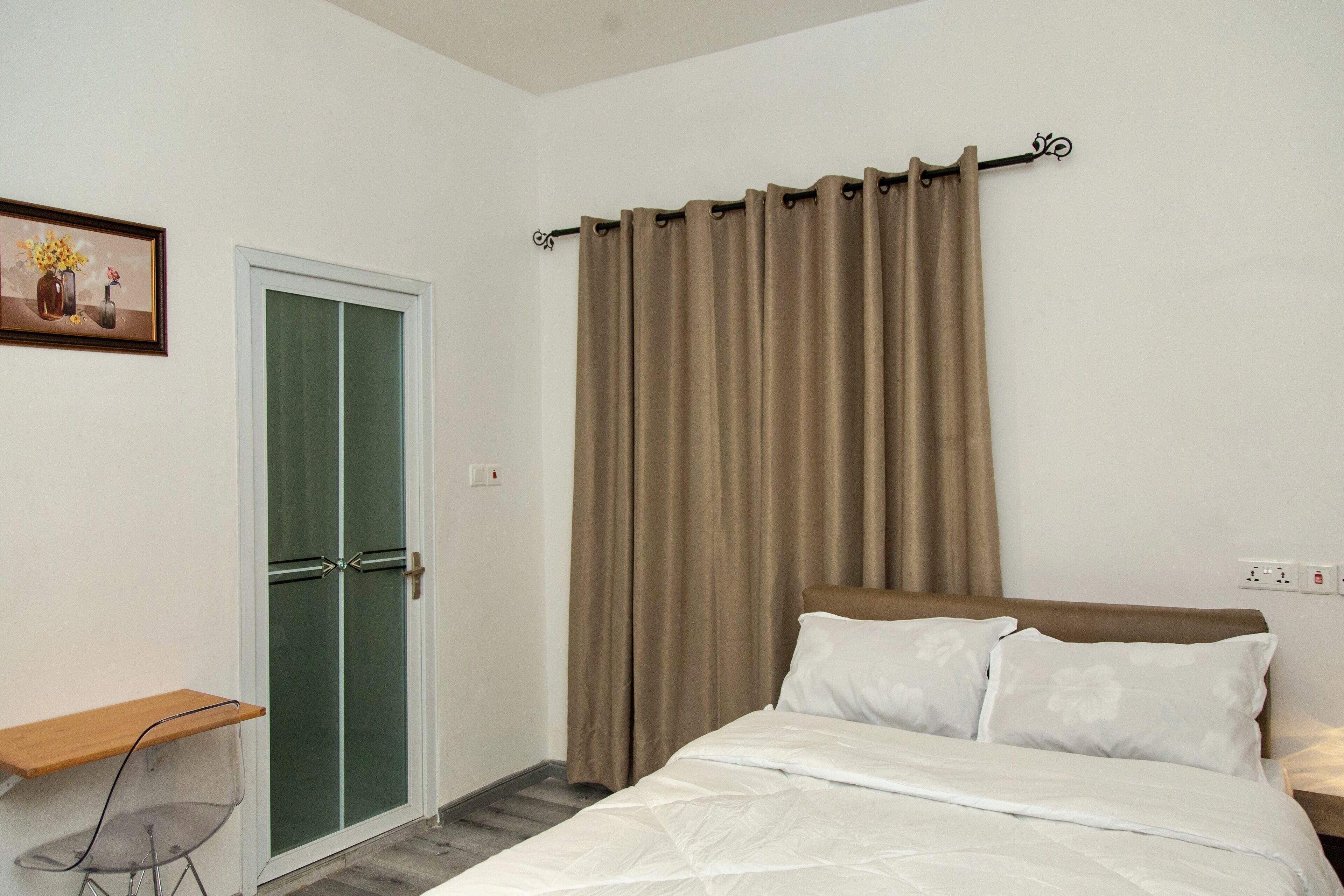 Un dormitorio con cama, escritorio, silla y puerta con paneles de vidrio esmerilado.