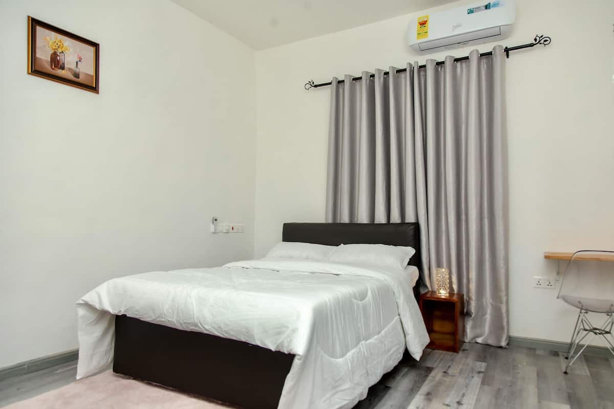Un dormitorio con cama, escritorio y aire acondicionado instalado en la pared.