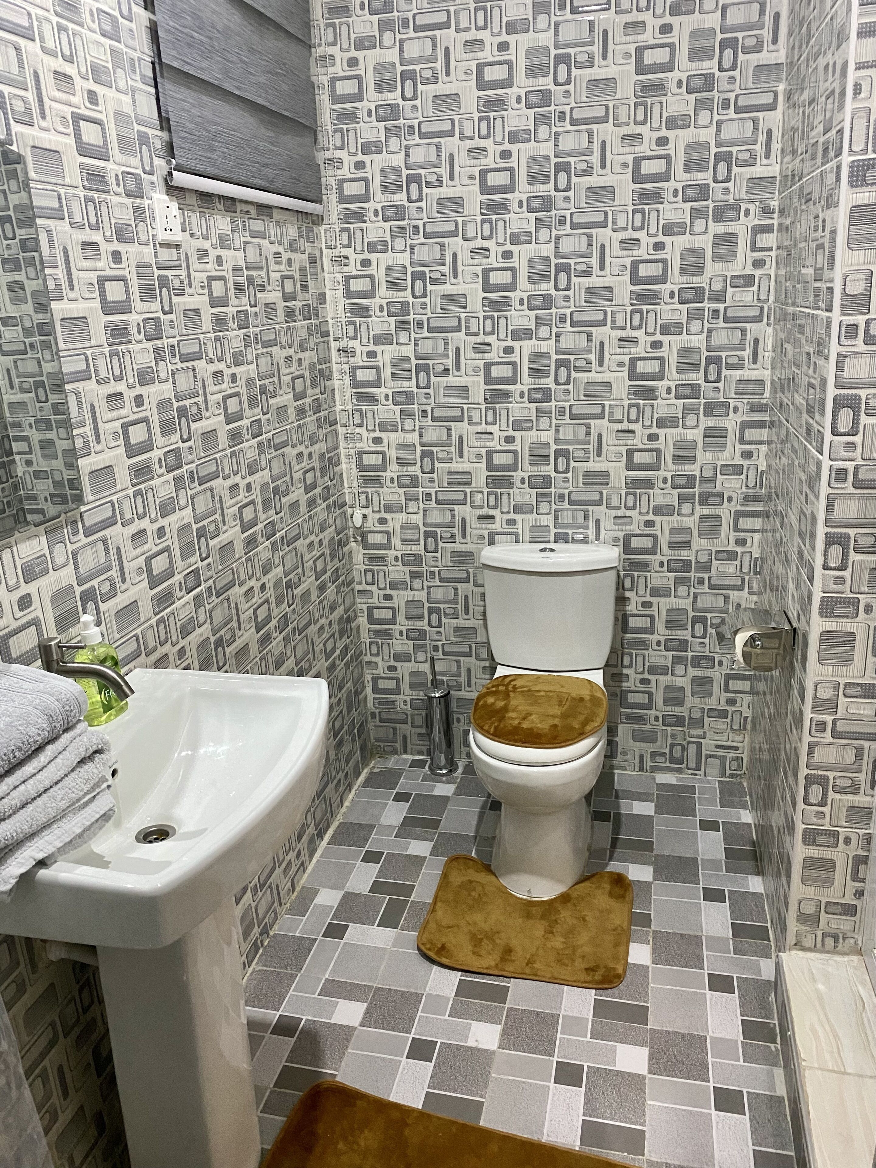 Un bagno con piastrelle decorate, un lavandino bianco e un water con la tazza marrone.