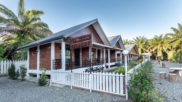 A two-story building with a white picket fence, a signboard, and a gravel driveway. - OYO 90149 Pua Family Semporna (Semporna)