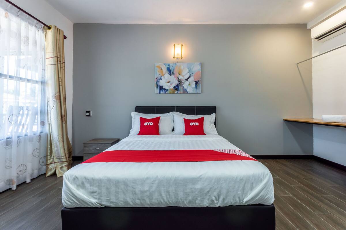 Habitació d'hotel amb un llit gran, una tauleta de nit, una làmpada penjada a la paret i un quadre.