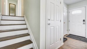 A staircase with wooden steps leading to a white door with a keyhole. - Panoramic Point - Downtown King Full Kitchen (Colorado Springs)