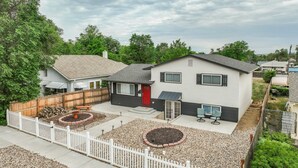 A two-story house with a red door, a covered patio with outdoor seating, and a fenced backyard. - Panoramic Point - Downtown King Full Kitchen (Colorado Springs)