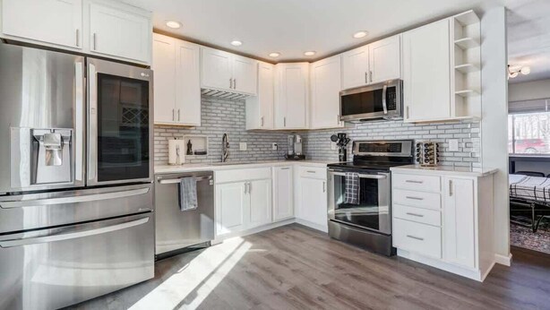 A modern kitchen with white cabinetry, stainless steel appliances, and a brick backsplash. - Panoramic Point - Downtown King Full Kitchen (Colorado Springs)