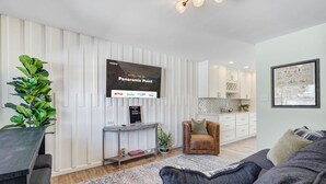 A modern living room with a flat-screen TV, a sofa, a coffee table, and a potted plant. - Panoramic Point - Downtown King Full Kitchen (Colorado Springs)