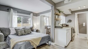 Een moderne, goed verlichte slaapkamer met een groot bed, een kleine kitchenette en uitzicht op het omliggende landschap.