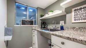 Cocina compacta con encimera de granito, pileta integrada, cafetera y un cartel de bienvenida a Colorado Springs.