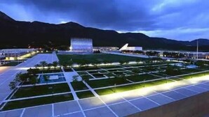 Un edificio moderno con una fachada distintiva y una plaza bien iluminada con jardines geométricos.