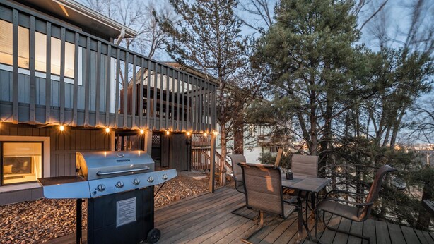 Terraza al aire libre con una parrilla, zona de estar y luces colgantes.