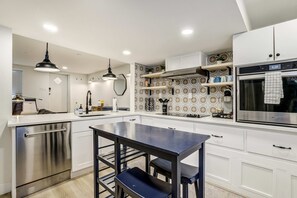 Una cocina moderna con armarios blancos, lavavajillas de acero inoxidable, un lavamanos doble y horno empotrado.