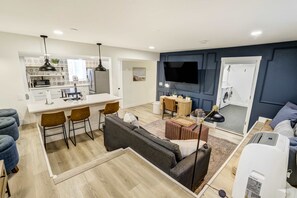 A modern living space with a kitchen, dining area, and a seating area with a sofa and chairs.