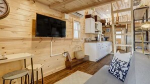 A wooden interior with a TV, kitchenette, and seating area.