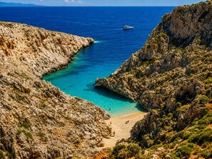 Eine Küstenlandschaft mit schroffen Klippen, blauem Meer und einem Sandstrand.