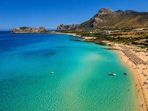 Un paysage côtier caractérisé par une eau turquoise cristalline, des affleurements rocheux et une plage de sable.