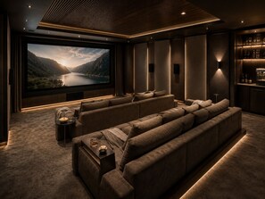Une salle de cinéma privée dotée d’un grand écran, de sièges confortables et d’un espace bar.