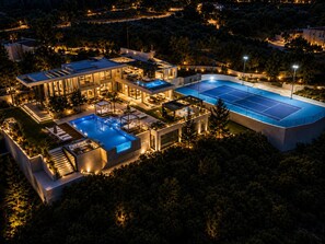 Una casa moderna con piscina, mobiliario de exterior y cancha de tenis.