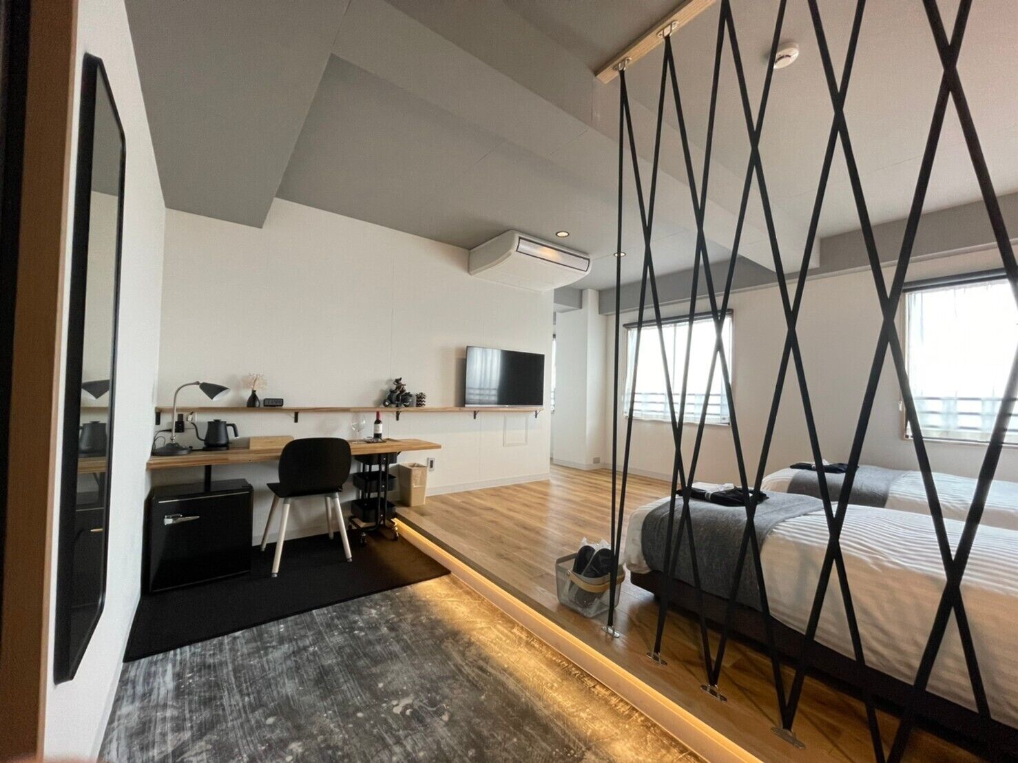 A modern bedroom with a bed, a desk, and a television.