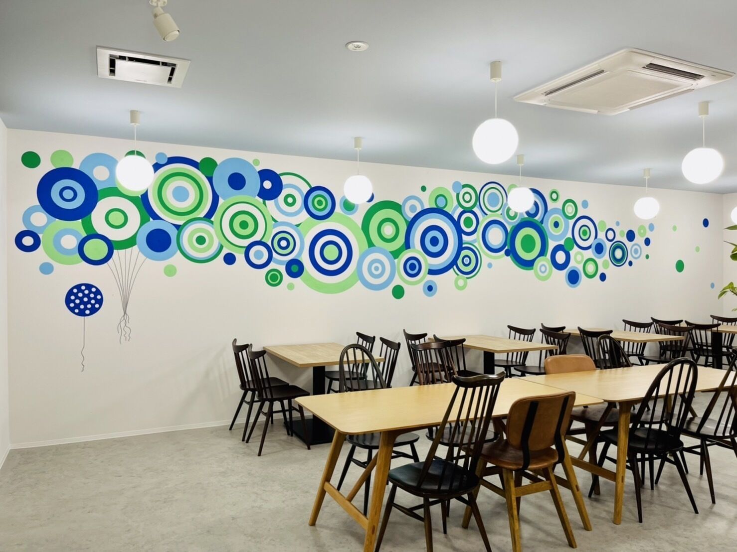 A conference room with a long table and chairs, a ceiling with circular wall art, and air conditioning vents.