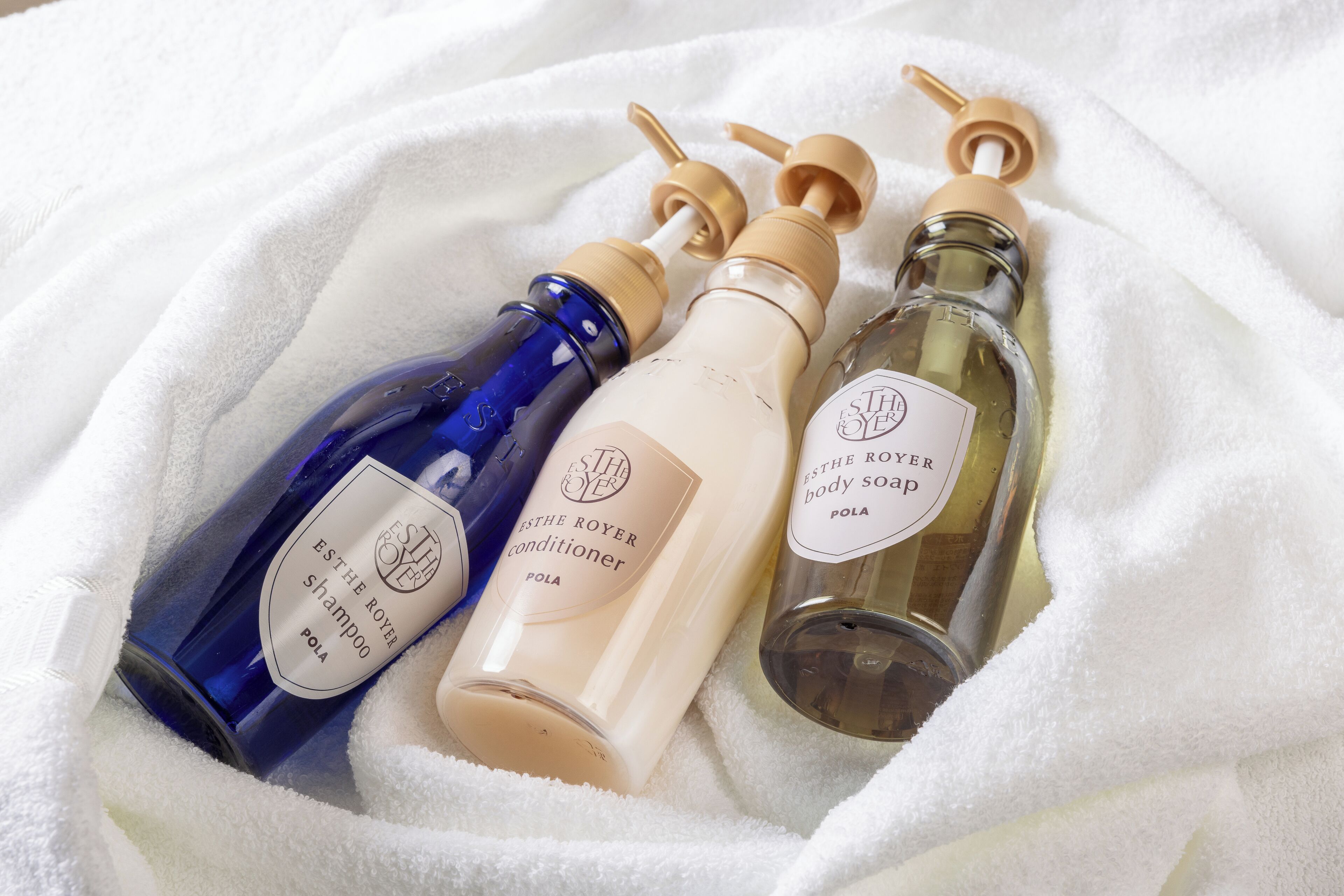 Three bottles of body care products on a white towel.