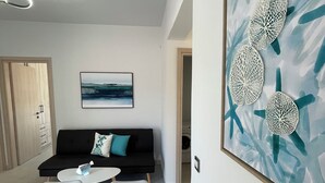 A modern room with a sofa, a dining table, and a wall-mounted artwork.