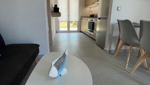 A modern kitchen with built-in appliances, a dining area with a table and chairs, and a view through a glass door.