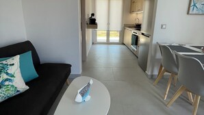 A modern living room with a sofa, a coffee table, and a dining area with chairs.