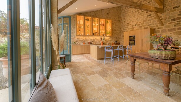 A rustic kitchen with stone walls, wooden beams, and a large window. - La Glycine (Tonnac)