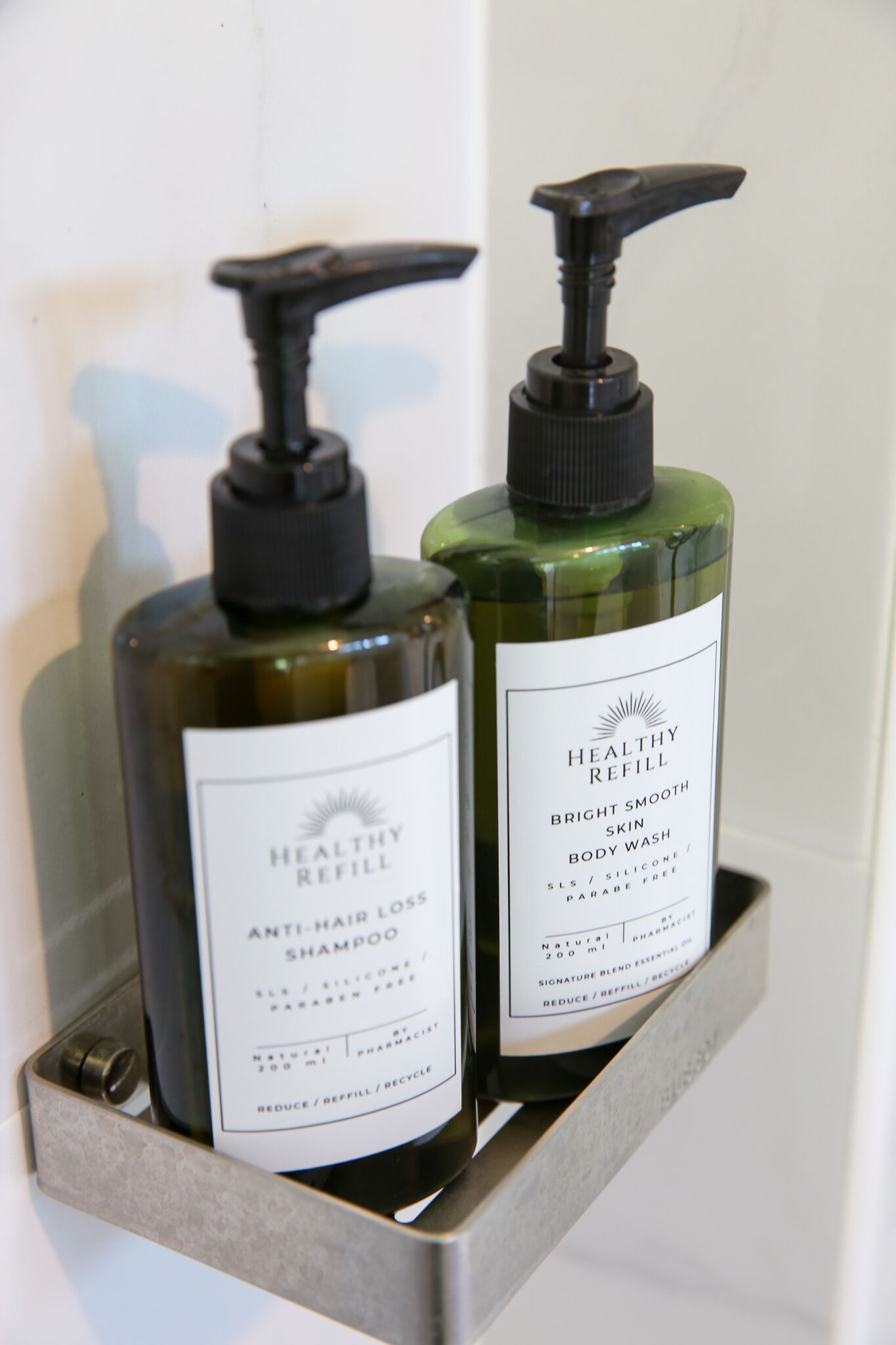 Two bottles of body wash in a bathroom shelf.