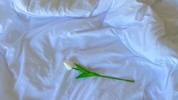 A white bedspread with a single white tulip flower.
