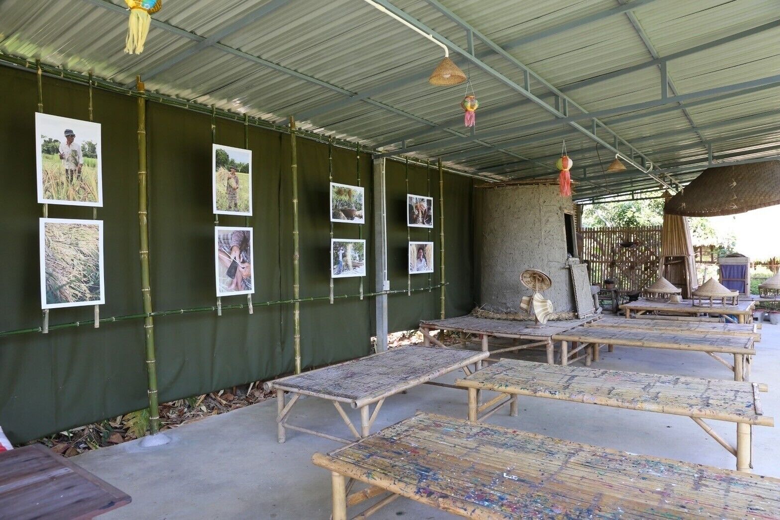 A covered outdoor area with bamboo furniture and a wall displaying photographs.