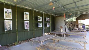 A covered outdoor area with bamboo furniture and a wall displaying photographs.