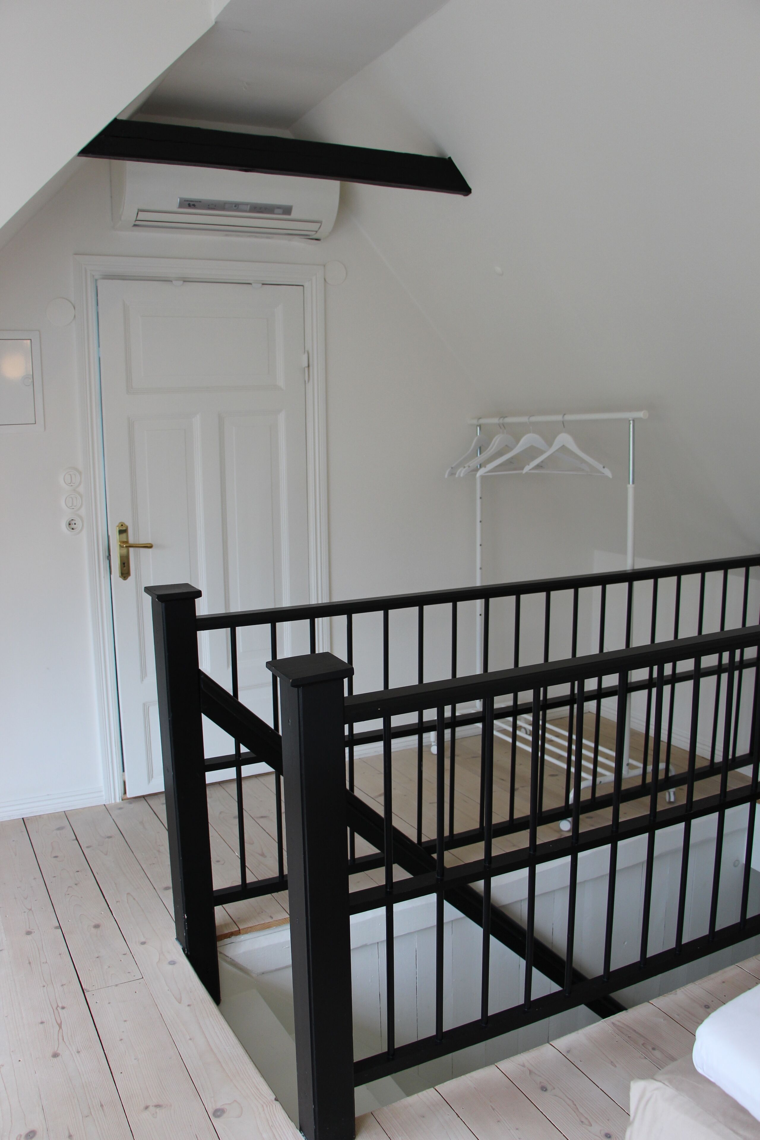 A staircase with a black railing, a white door, and a white wall with a clothes drying rack.