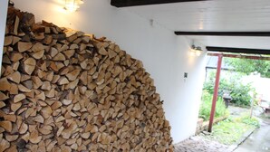 Ein Holzstoß an einer weißen Wand, darüber eine Lampe.